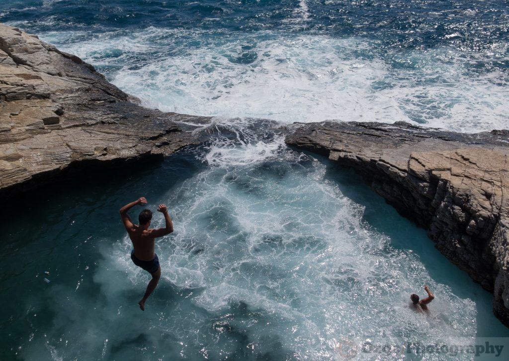 man jumping from the cliff into Giola, Thassos, Greece